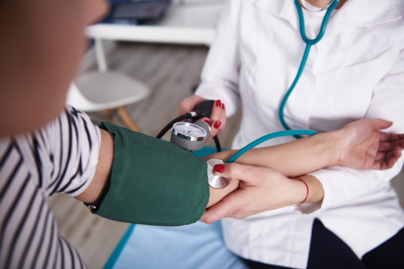 Doctor taking blood pressure of woman in medical practice
